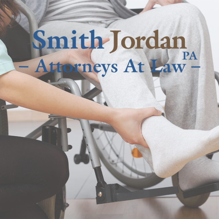Caregiver supporting patient's leg in wheelchair, Smith Jordan Attorneys at Law logo overlay
