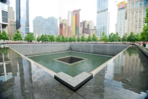 Reflecting pool at the September 11 Memorial in New York City with surrounding skyline and trees