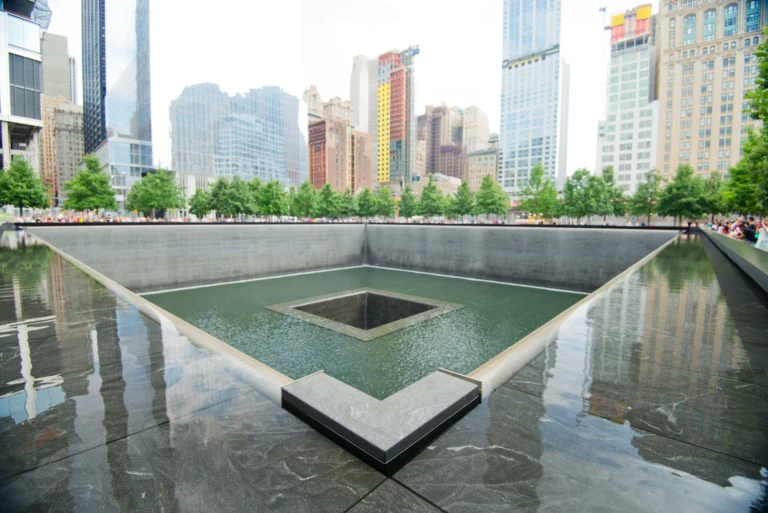 Reflecting pool at the September 11 Memorial in New York City with surrounding skyline and trees