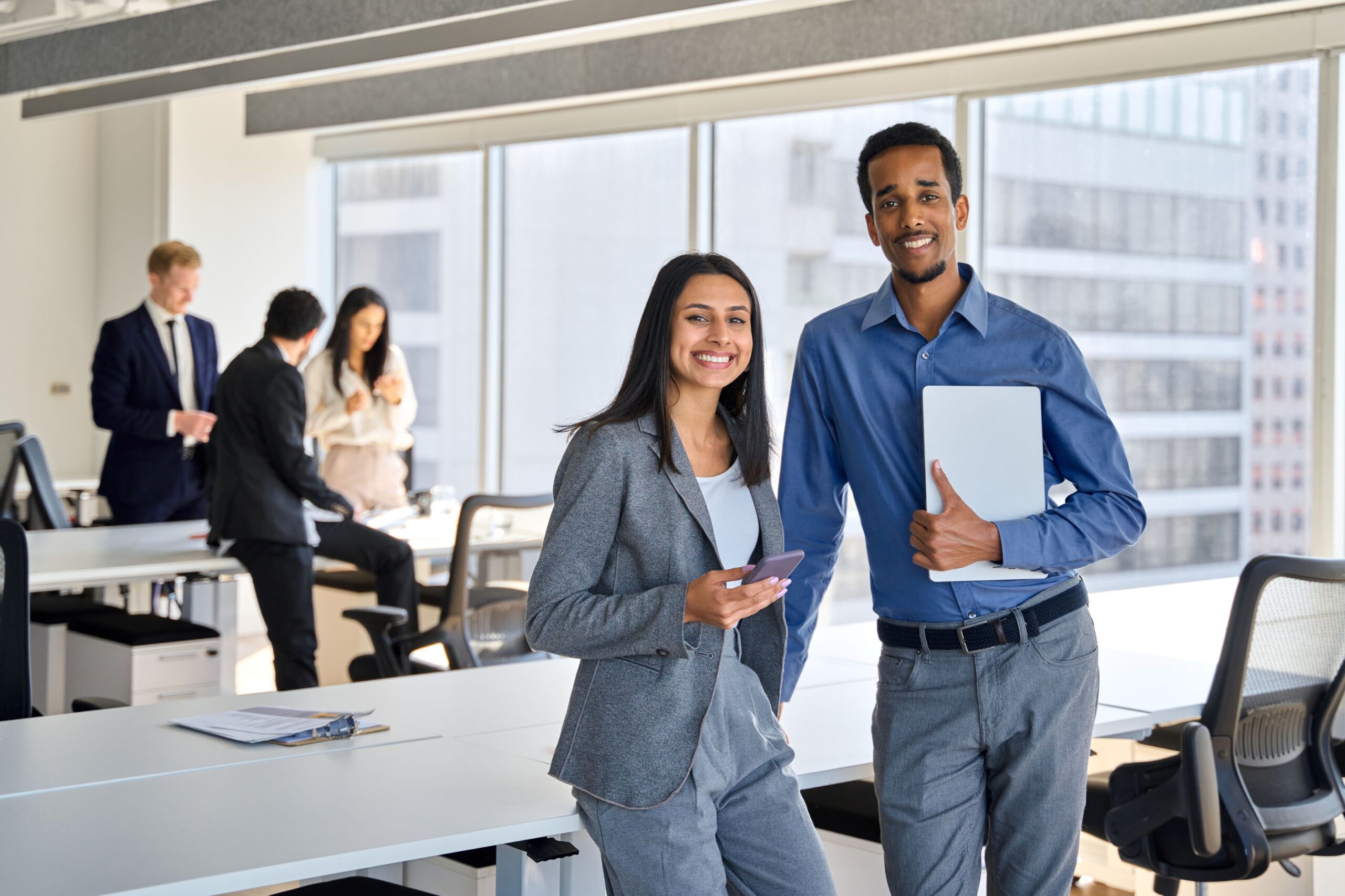 A group of white-collar workers engaged in a business meeting around a conference table with laptops and presentation materials.